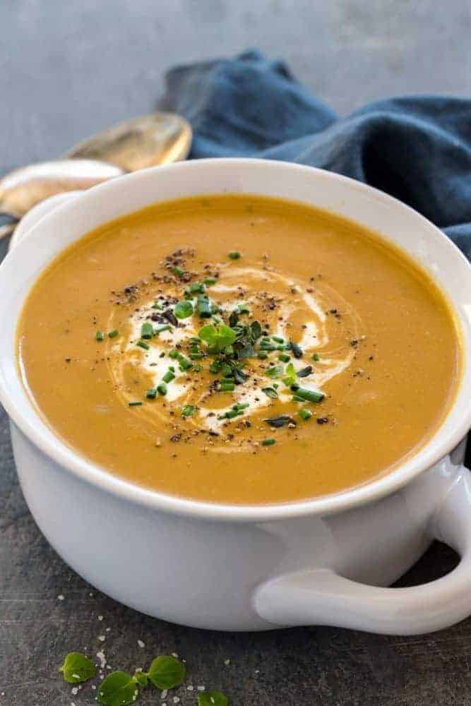 Slow Cooker Potato Leek Soup serves up a satisfying bowl of creamy pureed vegetables. The caramelized onions and leeks bump up the flavor as it gently simmers with the flaky potatoes and herbs. You wonโt believe how easy it is to create a restaurant quality dish in the crock-pot! White bowl of potato leek soup.