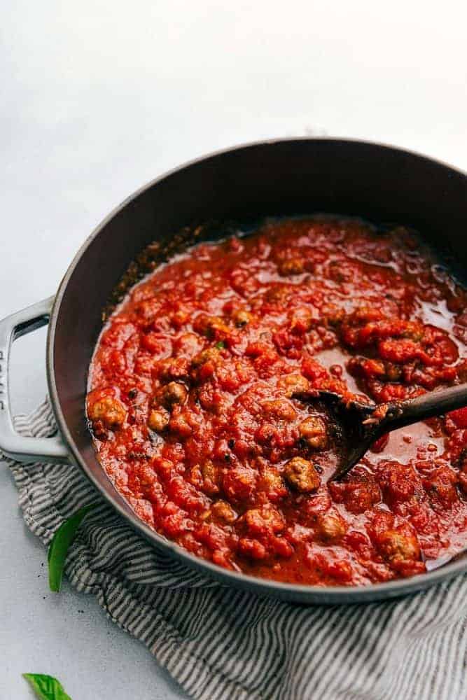 Sausage Tomato Gnocchi is a flavorful tomato sauce with miniature sausage "meatballs" served over gnocchi. A quick and easy meal that the family will all go crazy for!ย Tomato sauce being cooked any sauce pan using a wooden spoon.