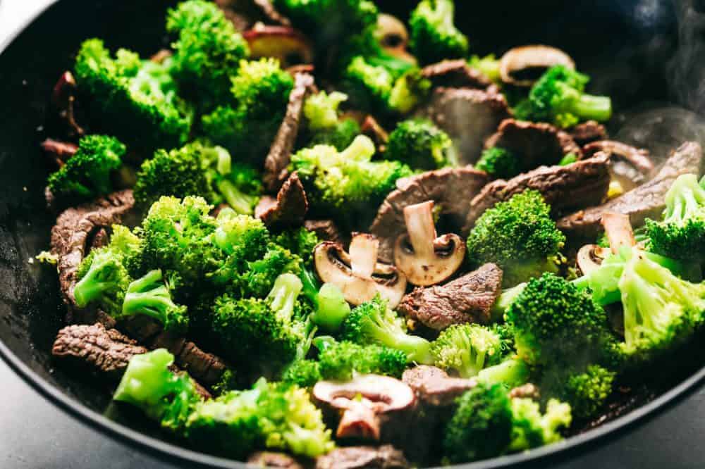 Garlic Beef and Broccoli Noodles is made with tender melt in your mouth beef in the most amazing garlic sauce. Add some mushrooms, broccoli and noodles for an amazing meal in one! Broccoli mushrooms and garlic are being stir fried together.