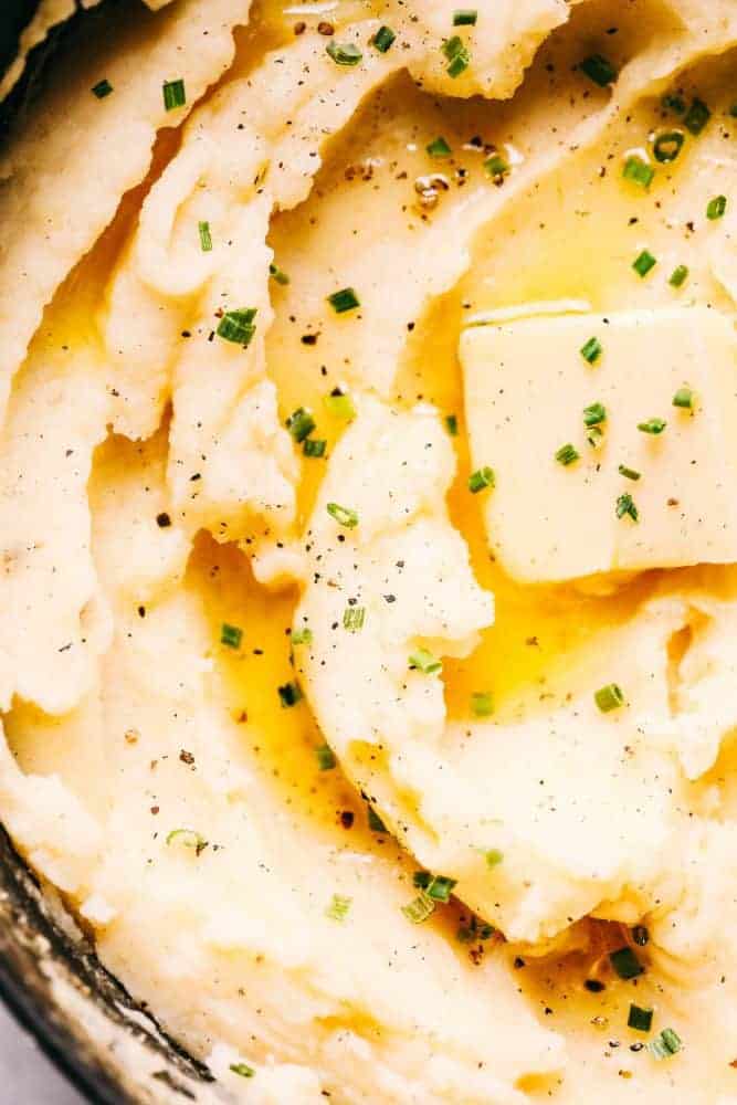 My dad's famous mashed potatoes are always the star of the dinner table! Perfectly creamy, buttery, and they have such amazing flavor. People are always begging him to make the recipe! Closeup of potatoes topped with butter.