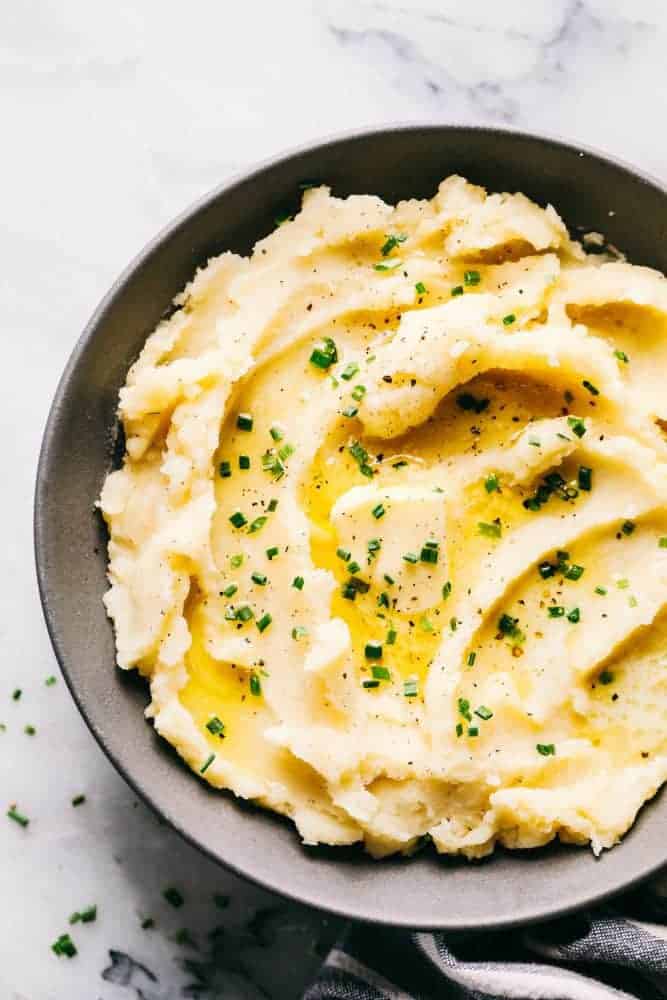 My dad's famous mashed potatoes are always the star of the dinner table! Perfectly creamy, buttery, and they have such amazing flavor. People are always begging him to make the recipe! A serving in a gray bowl.