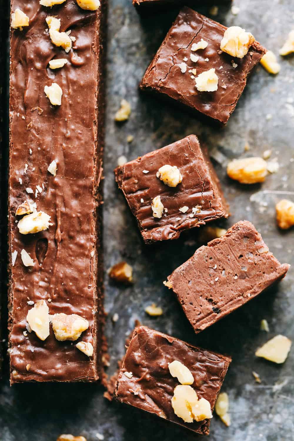 Fantasy Fudge is the creamiest, dreamiest most delicious classic fudge recipe. The fudge just melts in your mouth and is so easy to make with no thermometer required! Fantasy fudgeWith the long strip next to it has cut up 1 inch pieces of fudge with walnuts chopped over top and a black countertop.