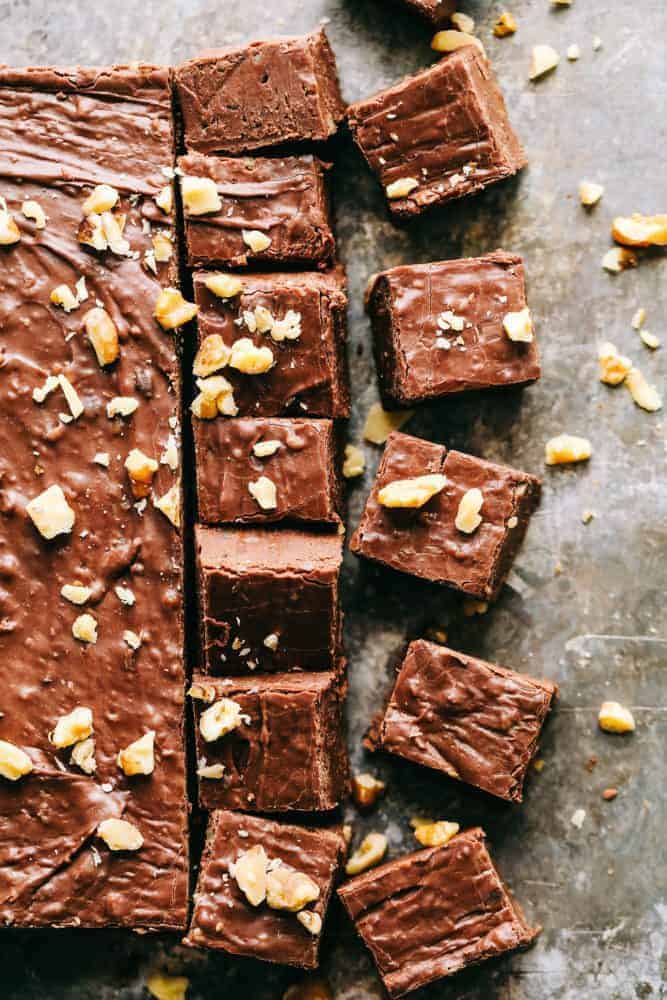 Fantasy Fudge is the creamiest, dreamiest most delicious classic fudge recipe. The fudge just melts in your mouth and is so easy to make with no thermometer required! Fantasy fudge cut into pieces garnished with walnuts.