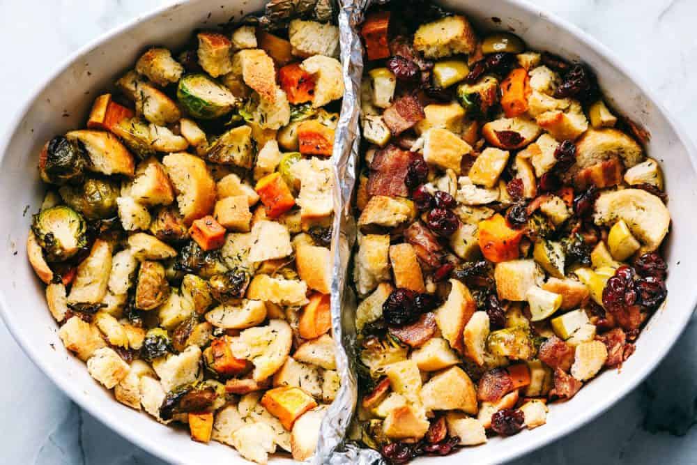 Roasted Autumn Vegetable Stuffing is the perfect side dish for your holiday meal. Filled with roasted autumn vegetables and bacon, this is the perfect addition to the dinner table. Roasted autumn vegetable stuffing and a white dish with an aluminum foil divider in the middle