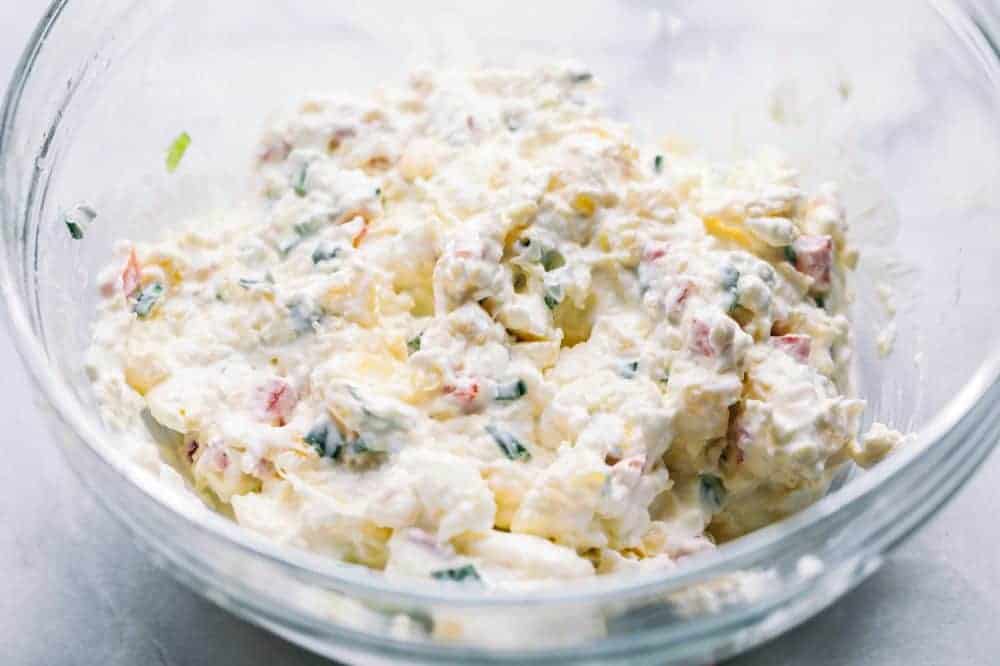 Pineapple Cheese Ball is the next best twist on a favorite classic. With Different textures and flavors it will be the hit at your next gathering! Pineapple cheese ball ingredients mix together in a glass bowl.