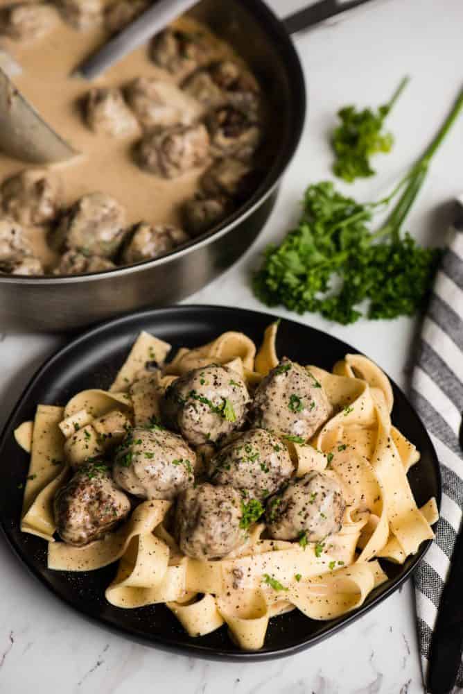Swedish Meatball Pasta combines flavorful homemade pork and beef Swedish meatballs with a heavenly cream sauce and perfectly cooked pasta. Swedish Meatball Pasta on a black plate garnished with fresh parsley