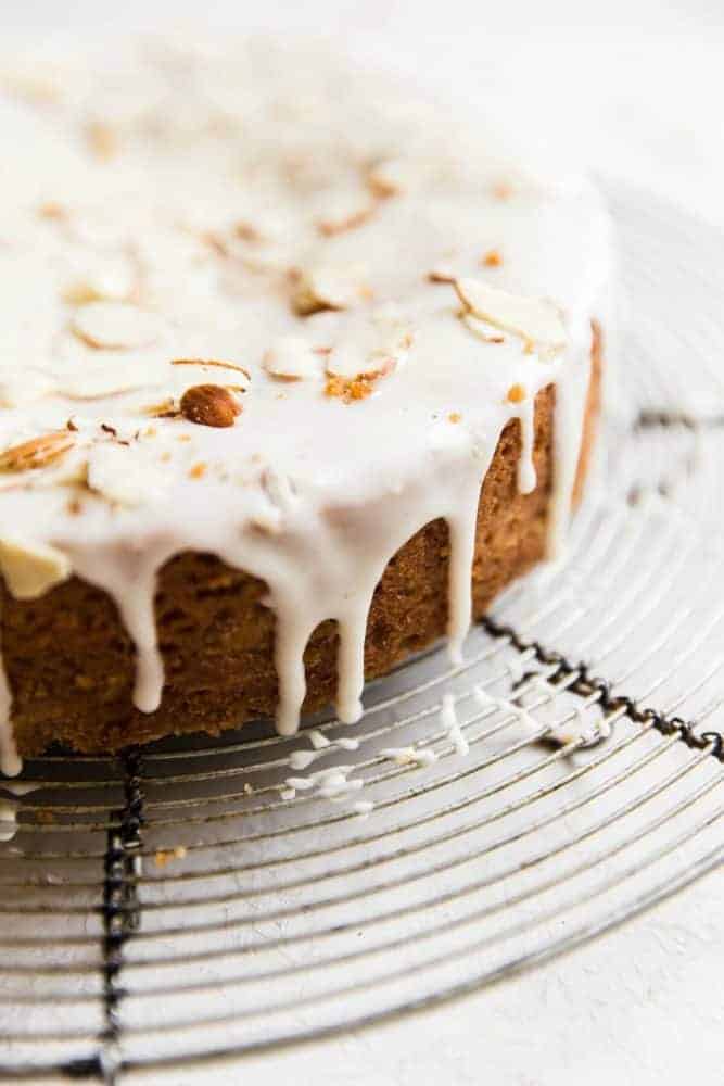 Easy Brown Butter Almond Cake is an incredibly delicious and moist cake with a brown butter icing. This is seriously one of the best cakes that I have EVER had! This is a must-make for that baking list! Close up photo of brown butter almond cake on a cooling rack with sliced almonds on top.