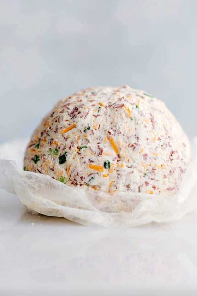 Chipped Beef Cheese Ball is such a classic and amazing cheeseball filled with cheddar cheese, cream cheese, green onions, and dried beef. This easy cheese ball is going to be the hit at any gathering!ย Chipped beef cheese ball on parchment paper.