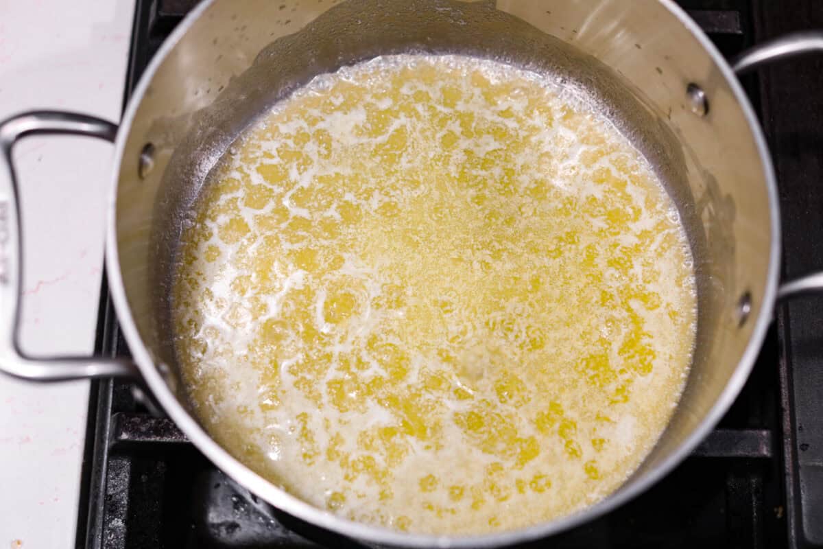 Christmas Cornflake wreaths are a fun, whimsical treat that symbolizes infinite love during the holiday season. Crunchy cornflakes, bright green food coloring, and a sweet, gooey glaze combine to make the cutest Christmas wreath treats. Overhead shot of melted butter in a saucepan.