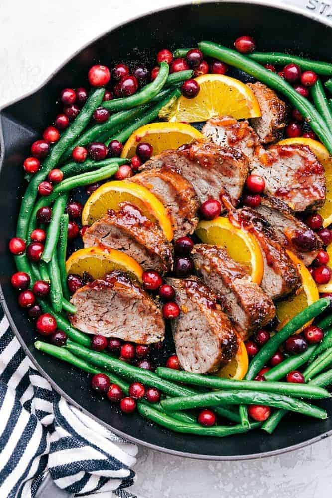Roasted Cranberry Orange Pork Tenderloin with Green Beans is such a flavorful and easy meal. The cranberry orange glaze is perfect on top of the pork and green beans. This will be the star of your holiday dinner table! Roasted cranberry orange pork tenderloin with green beans in a skillet.