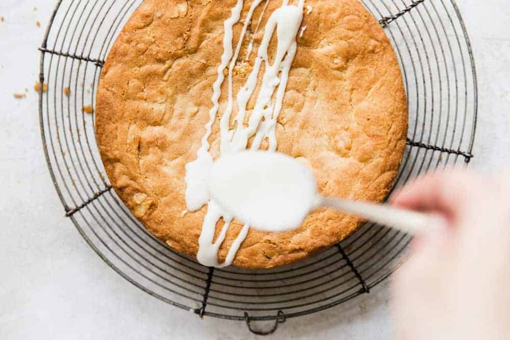Easy Brown Butter Almond Cake is an incredibly delicious and moist cake with a brown butter icing. This is seriously one of the best cakes that I have EVER had! This is a must-make for that baking list! Spoon drizzling almond topping over brown butter almond cake.