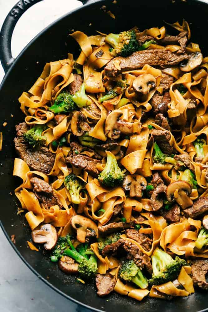 Garlic Beef and Broccoli Noodles is made with tender melt in your mouth beef in the most amazing garlic sauce. Add some mushrooms, broccoli and noodles for an amazing meal in one! Garlic beef and broccoli noodles in a black skillet.