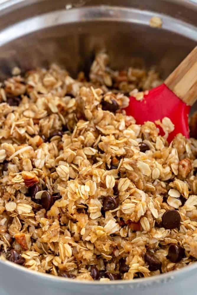 Cowboy Cookies are thick and chewy treats loaded with chocolate chips, oats, shredded coconut, pecans, and cinnamon. Incorporating browned butter into the cookie dough enhances the nutty, caramel notes of the cookie. This recipe packs delightful flavors and textures sure to satisfy any sweet tooth. Mixing the cowboy cookie dough in a metal bowl.