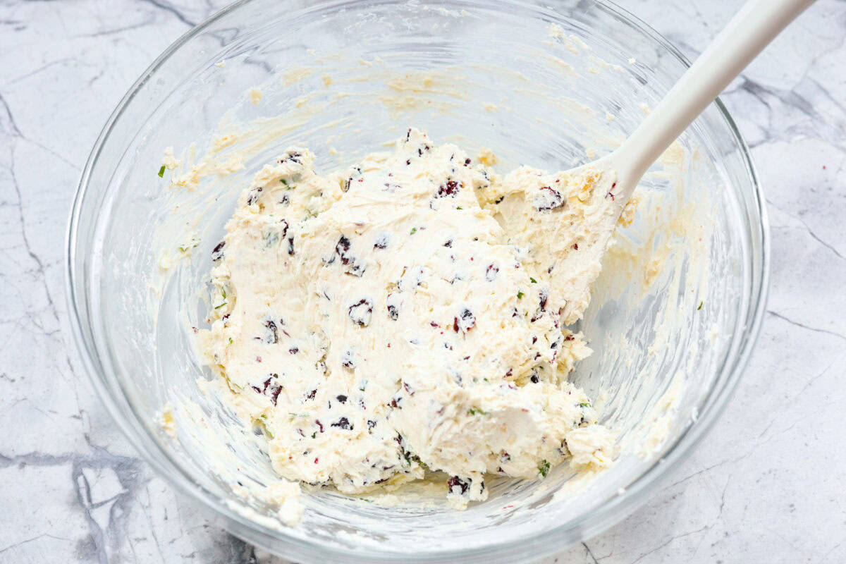 This festive cranberry pecan cheese ball is an easy appetizer for the holiday season! Everyone will love this creamy cheese ball loaded with delicious texture from the dried cranberries and pecans. Serve this impressive appetizer with crackers and enjoy! Third photo of the cheese, cranberries, and onions mixed into the cream cheese mixture.