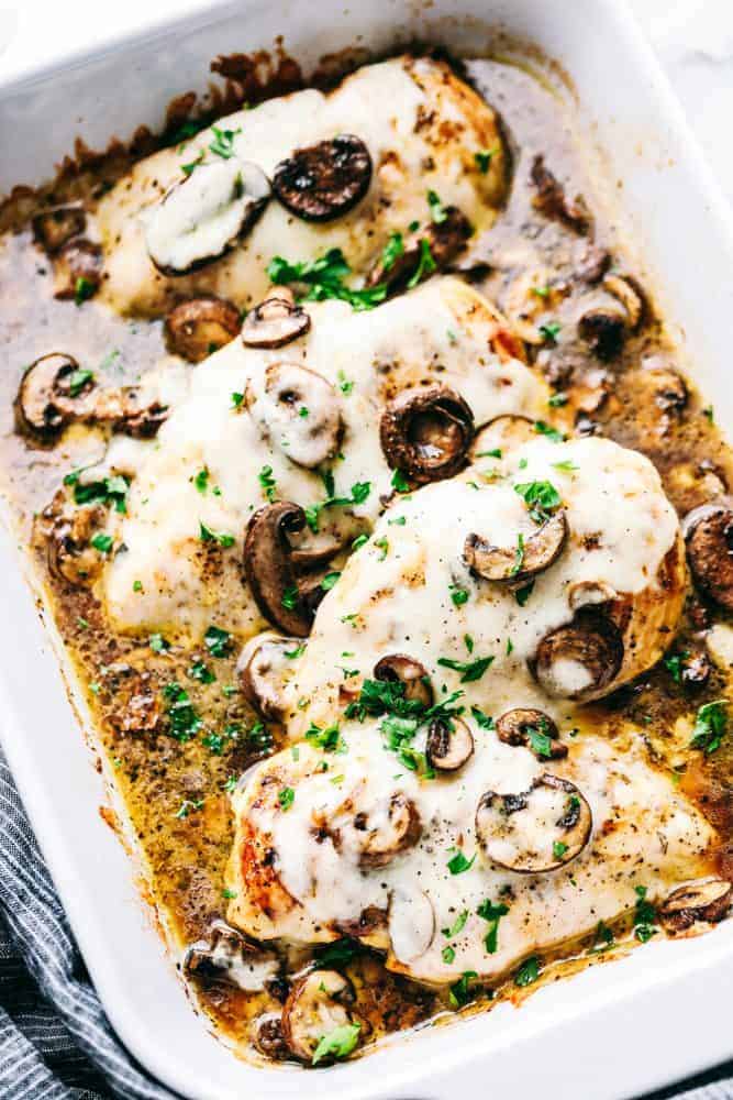 Easyย Baked Cheesy Mushroom Chickenย has a melted cheese covering the tender chicken breast with flavorful mushroomsย and mushroom sauce to enhance every bite. The cheese melts and blend the chicken and mushroom flavors together making a meal that isย unforgettable.ย Preparingย this meal is a breeze and givesย you more time to spend with your family!ย Easyย Baked Cheesy Mushroom Chicken in a baking pan.