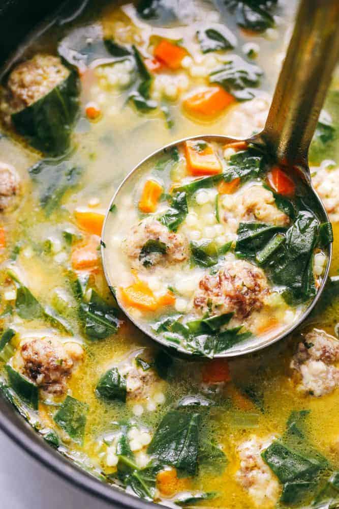 Italian wedding soup is warm and comforting and filled with tender chicken meatballs, veggies, and acini de Pepe. This classic Italian soup will become an instant family favorite! Italian wedding soup in a bowl with a ladle.