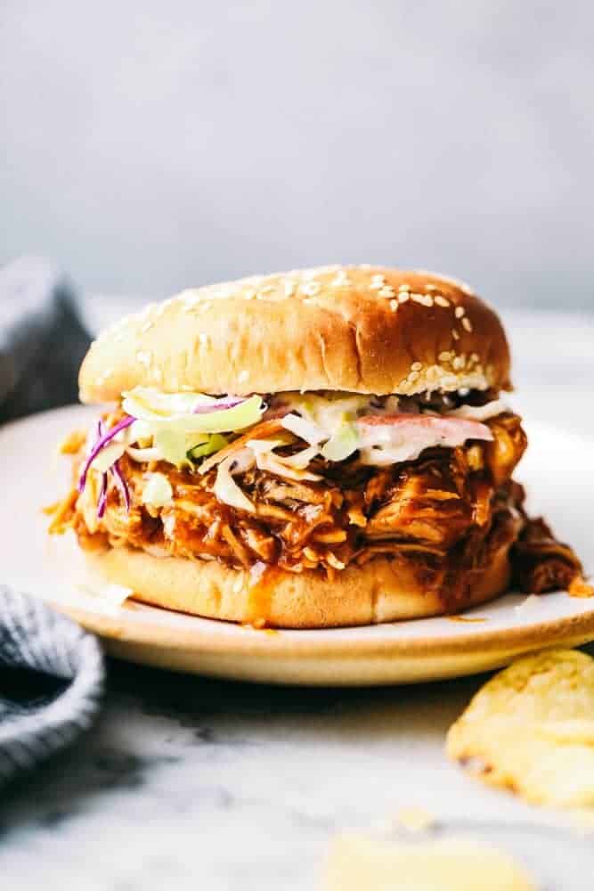 Slow Cooker BBQ Chicken slow cooks to perfection in the best sweet and tangy homemade BBQ sauce. The chicken is so tender and just melts in your mouth with the most amazing flavor! Slow Cooker BBQ Chicken sandwich on a plate.