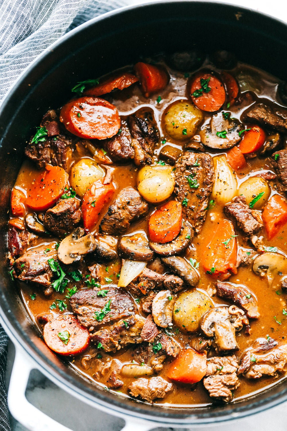 Beef Bourguignon is a French classic made with melt in your mouth beef, mushrooms, carrots, and red wine and is cooked to perfection in the most delicious rich sauce. A hearty and comforting meal that you will make again and again!ย Areal view of Beef Bourguignon.