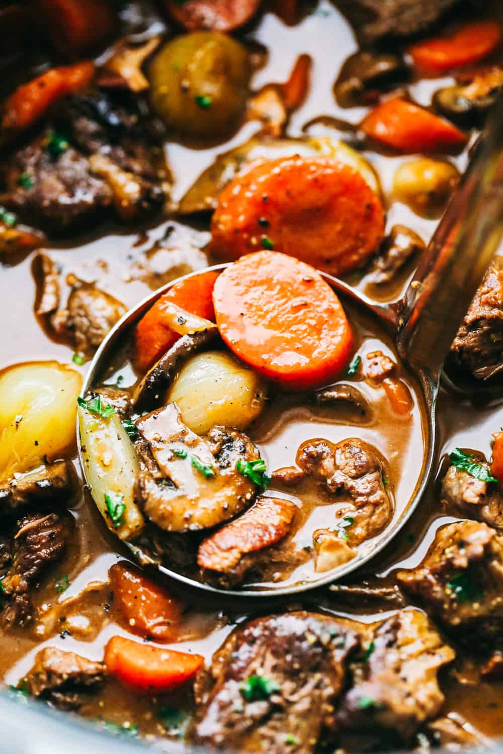 Beef Bourguignon is a French classic made with melt in your mouth beef, mushrooms, carrots, and red wine and is cooked to perfection in the most delicious rich sauce. A hearty and comforting meal that you will make again and again!ย Beef Bourguignon being scooped into a ladle.