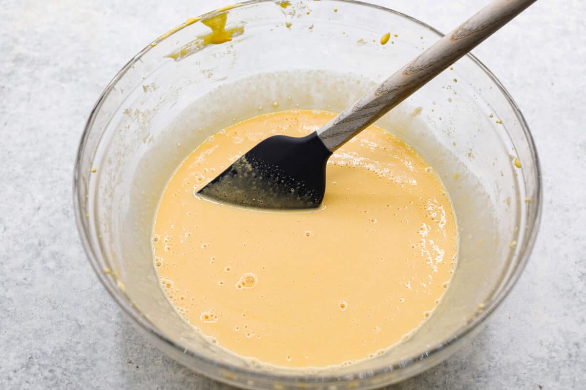 This tender Tres Leches cake is drenched in a three-milk mixture and is topped with fluffy whipped cream, cinnamon, or fresh fruit for a truly authentic Mexican dessert. Angle shot of egg yolk and sugar mixture with vanilla and milk added and stirred.
