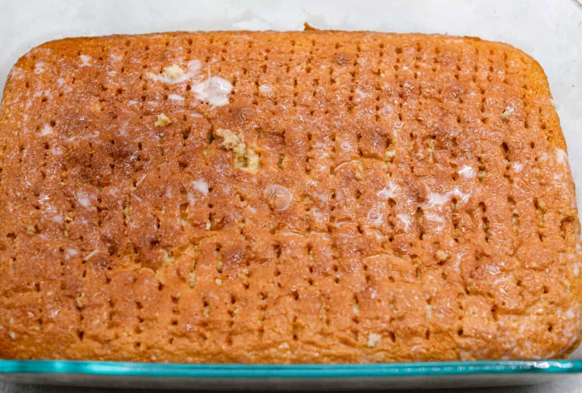 This tender Tres Leches cake is drenched in a three-milk mixture and is topped with fluffy whipped cream, cinnamon, or fresh fruit for a truly authentic Mexican dessert. Angle shot of the cake with fork pokes and milk mixture poured over the top. Making it a tres leches cake.