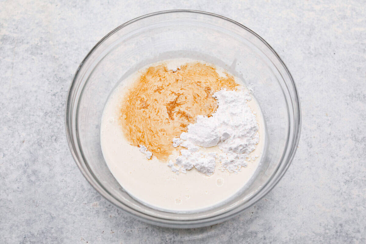 This tender Tres Leches cake is drenched in a three-milk mixture and is topped with fluffy whipped cream, cinnamon, or fresh fruit for a truly authentic Mexican dessert. Overhead shot of whipping cream powdered sugar and vanilla in a bowl.