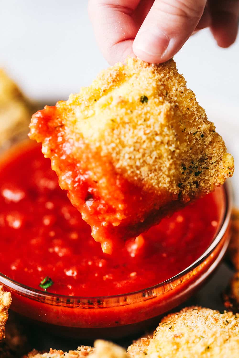 Crispy Baked Parmesan Ravioli are crunchy, crispy and filled with cheese and are perfect for dipping! These little bites are so addicting and good and will become a family favorite! Dipping Crispy Baked Parmesan Ravioli.