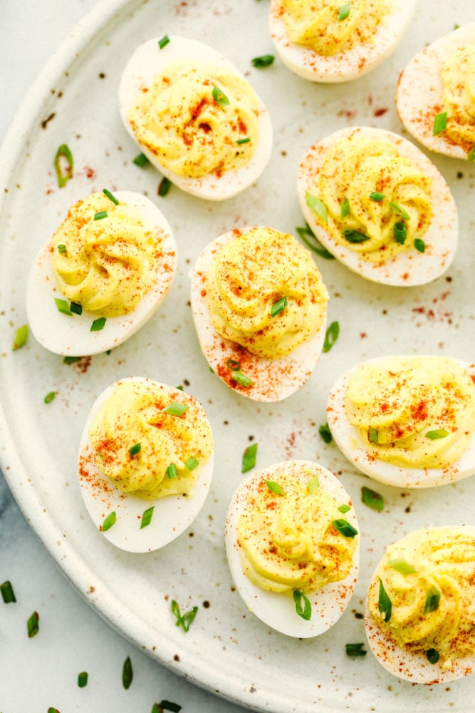 Classic Deviled Eggs are a favorite appetizer for parties and holiday celebrations. This traditional deviled egg recipe is simple and perfect! Deviled eggs on a plate with paprika sprinkled on top.