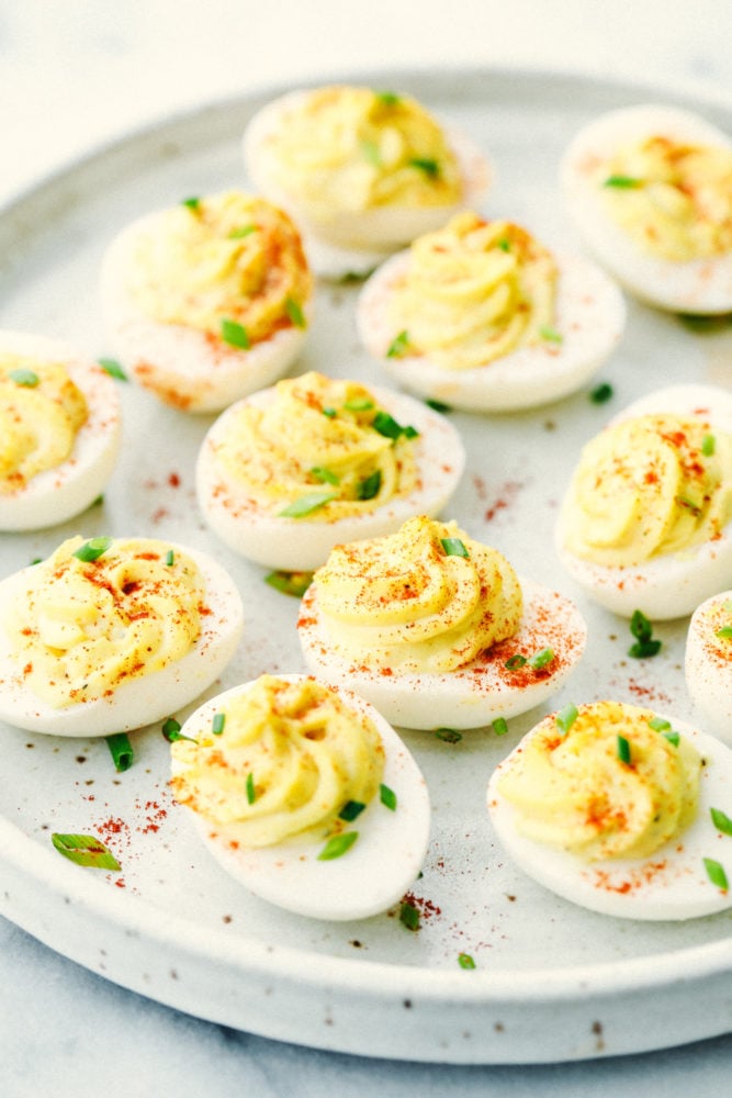 Classic Deviled Eggs are a favorite appetizer for parties and holiday celebrations. This traditional deviled egg recipe is simple and perfect! Deviled eggs on a plate with paprika sprinkled over top.