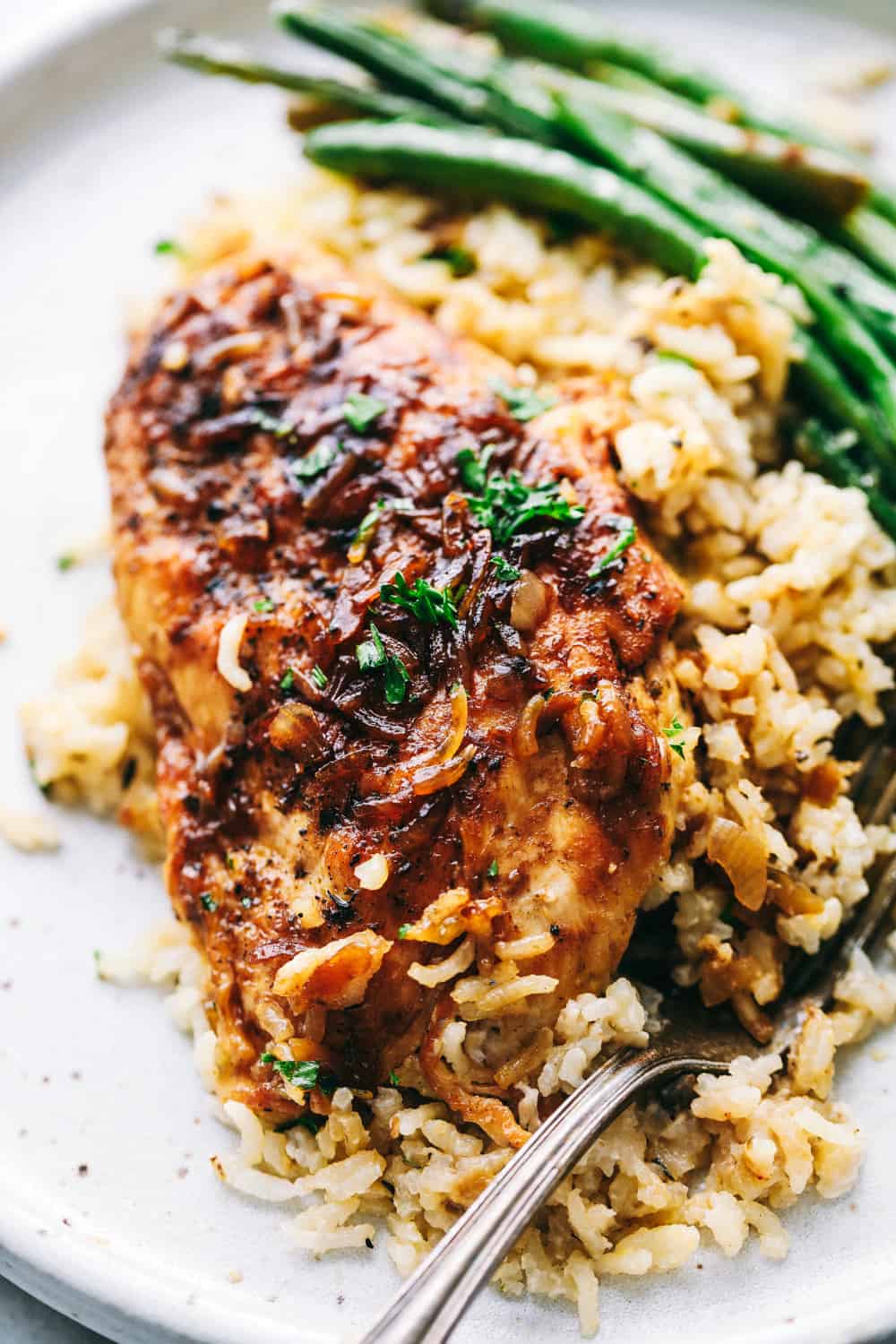 No Peek Chicken and Rice Casseroleย is full of comfort and tender, fall apart chickenย overtopping a flavorful rice thatย makes this meal a family favorite! Baking to perfection with the warm, steamย cooking the chicken and rice to perfection.ย No Peek Chicken and Rice Casseroleย on a plate with rice and veggie.