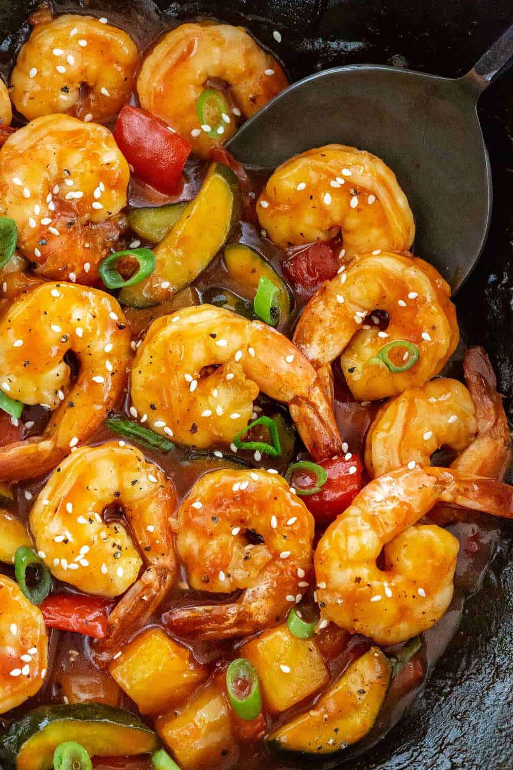 Sweet and Sour Shrimp is a quick Chinese meal made all in on pot! Succulent seafood is stir-fried with bell peppers, zucchini, pineapple and then tossed in a tangy honey sauce. This dish comes together in just 20 minutes for a simple and flavorful dinner. Sweet and Sour Shrimp in a wok