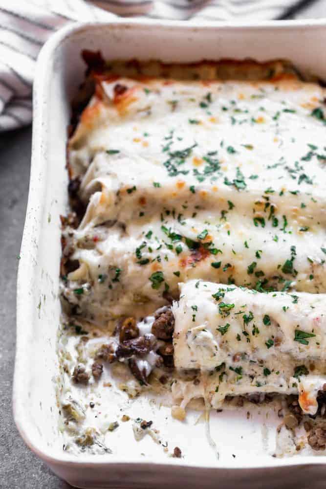 Salsa Verde Beef and Mushroom Enchiladas are SO easy to make, even on a weeknight! They're packed with a combo of beef and mushrooms, smothered in a creamy salsa verde sauce, and covered in shredded cheese. They'll become a new family favorite, guaranteed. Salsa Verde Beef and Mushroom Enchiladas in a pan.