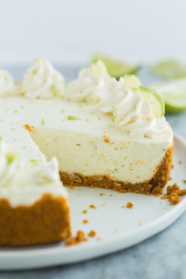 This No Bake Key Lime Cheesecake is so easy to make! It's light and fresh and made with fresh lime juice and real cream. It's got the perfect combination of creamy, tangy and sweet! #cheesecake #recipe #dessert no bake key lime cheesecake on white plate