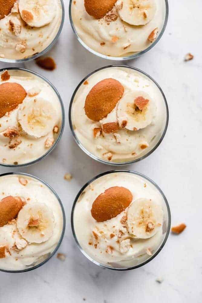 Magnolia Bakery Banana Pudding is a heavenly dessert made up of layers of creamy vanilla pudding, bananas, and Nilla Wafers. It's the very recipe that the famous New York City bakery uses! This delicious and easy recipe is sure to become a family favorite! Areal view of banana pudding in glass cups.