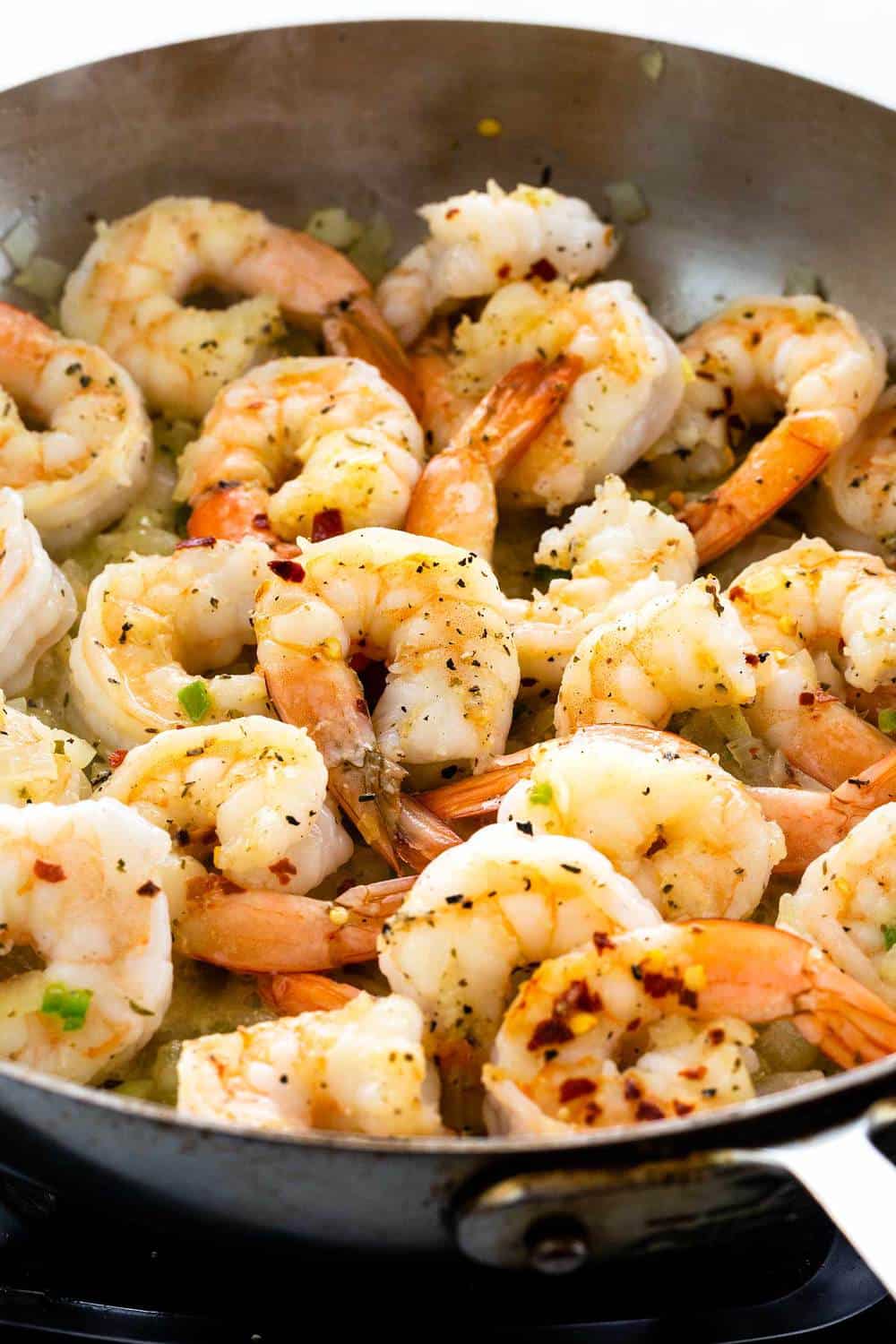 Shrimp Diablo is a fast and fiery Mexican dish for those who love a spicy kick! Succulent shrimp are sauteed with red pepper flakes, jalapenos, garlic, onions, green bell peppers and simmered in a rustic tomato sauce. Ready in just 30 minutes for a bold and flavorful meal. shrimp cooking in a skillet