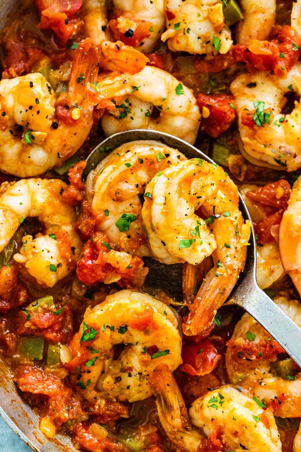 Shrimp Diablo is a fast and fiery Mexican dish for those who love a spicy kick! Succulent shrimp are sauteed with red pepper flakes, jalapenos, garlic, onions, green bell peppers and simmered in a rustic tomato sauce. Ready in just 30 minutes for a bold and flavorful meal. mixing shrimp diablo with a spoon
