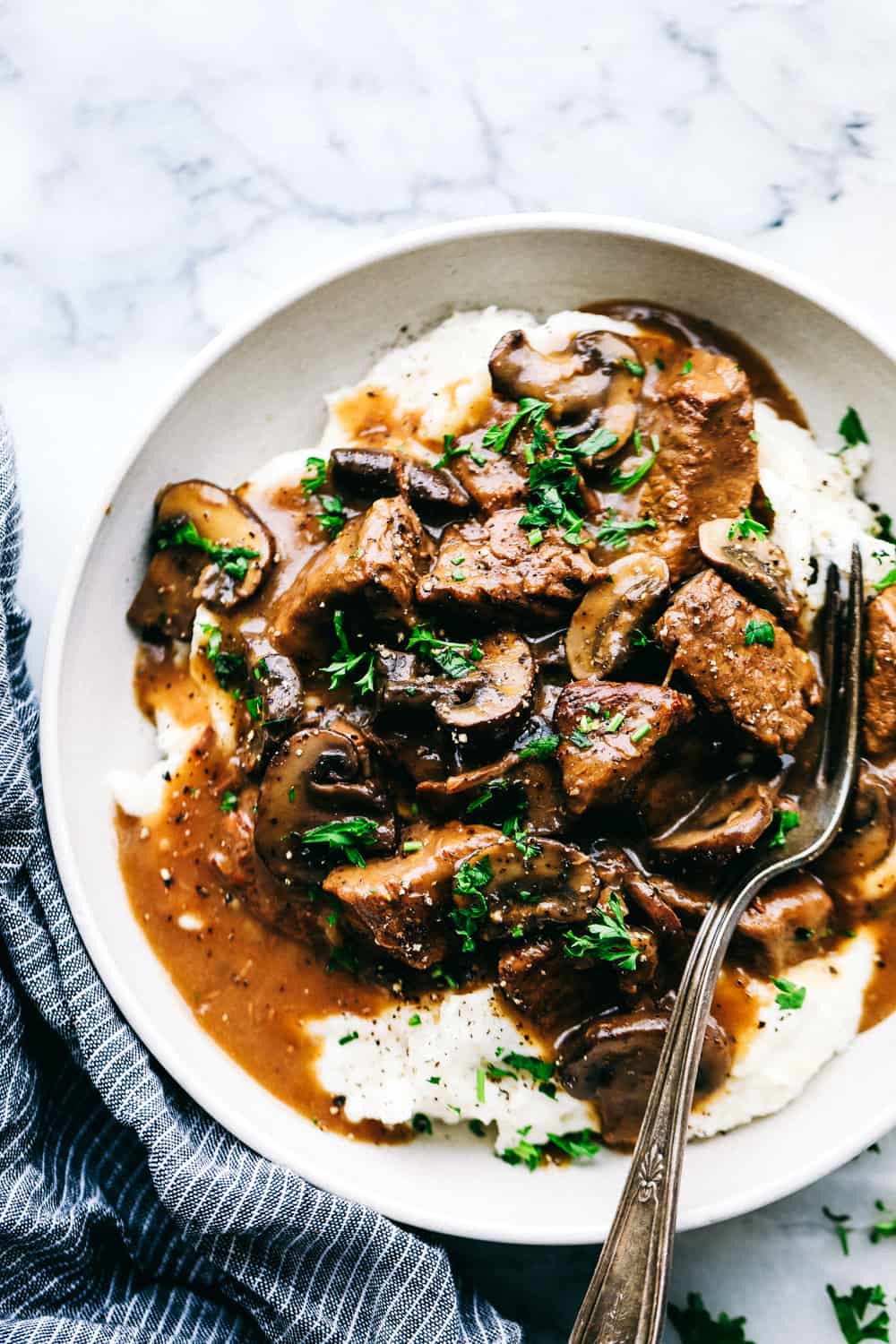 Slow Cooker Beef Tips are tender beef slices, mixedย with chopped mushrooms and onion mix slow cooked to perfection! Easy weeknight meal!ย slow cooker beef tips over mashed potatoes
