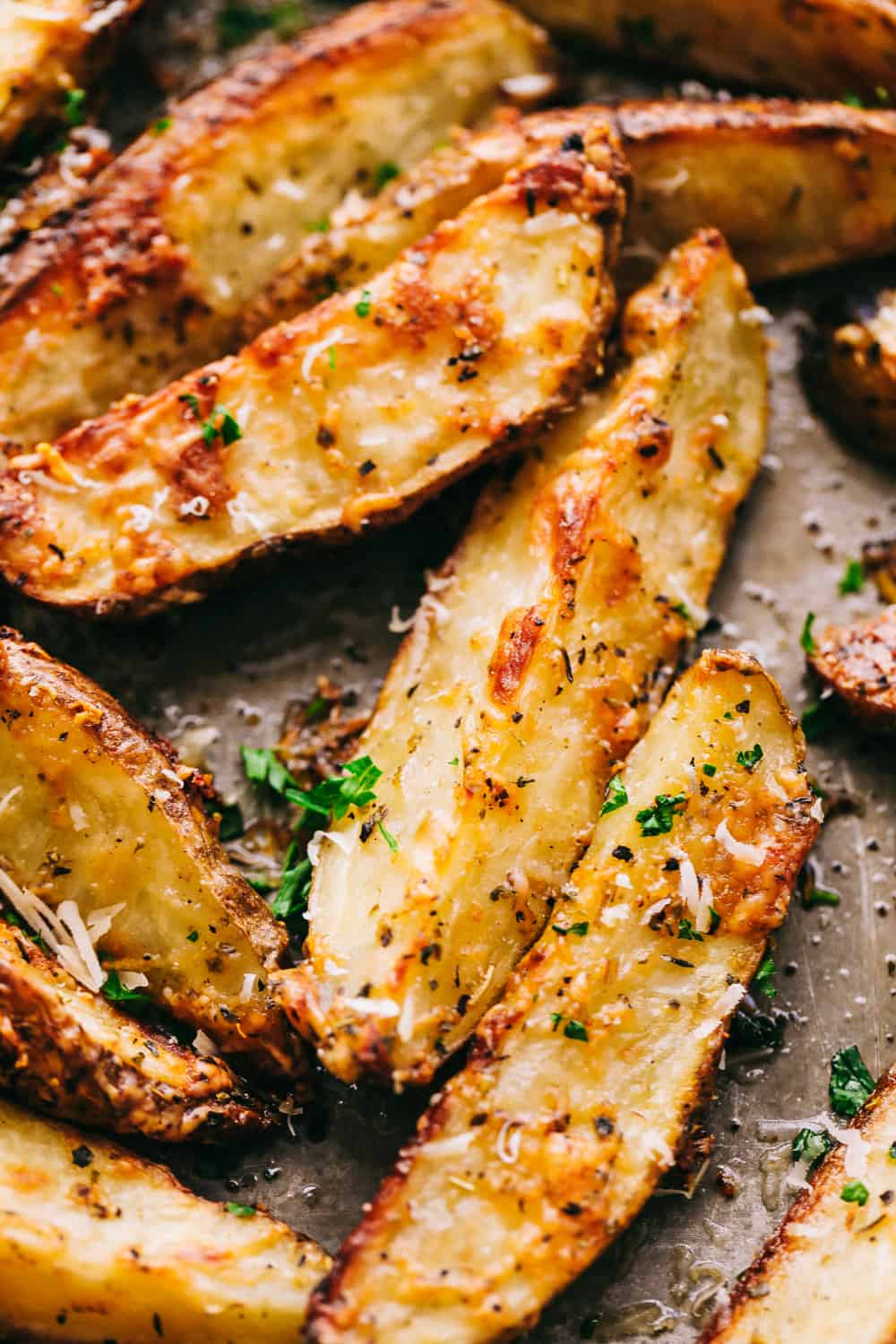 Baked parmesan garlic potato wedges are so incredibly easy and have the best savory flavor! These crispy wedges are roasted to perfection and guaranteed to be a huge hit. Grab your favorite dipping sauce and enjoy! Closeup of parmesan garlic baked potato wedges.