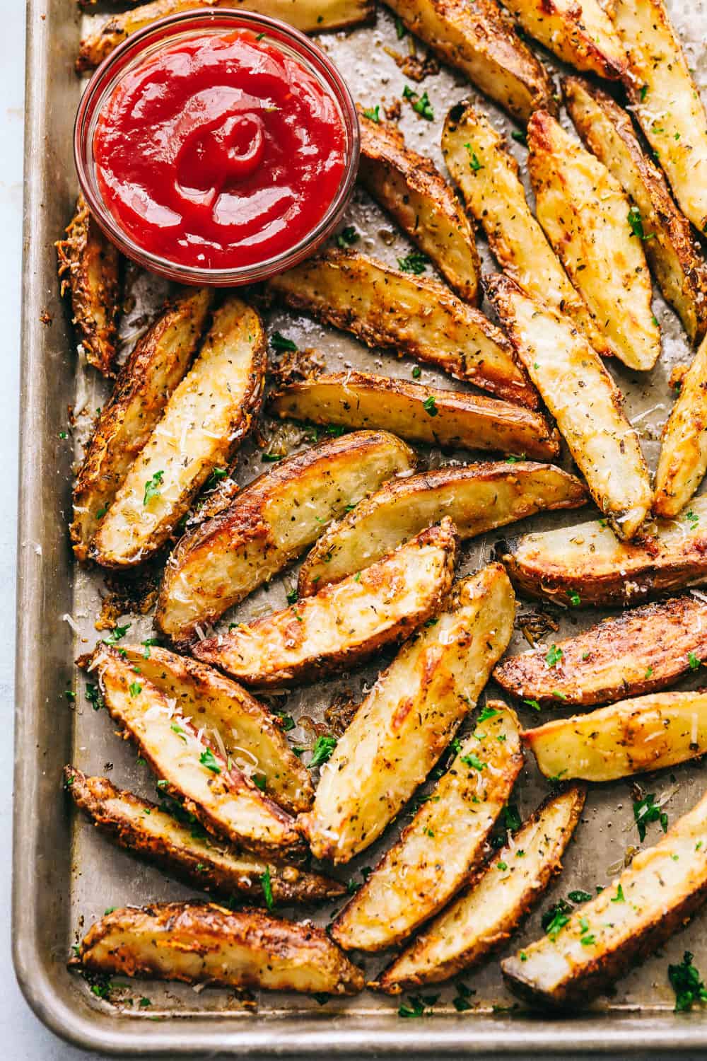 Baked parmesan garlic potato wedges are so incredibly easy and have the best savory flavor! These crispy wedges are roasted to perfection and guaranteed to be a huge hit. Grab your favorite dipping sauce and enjoy! The cooked potato wedges on a baking sheet.