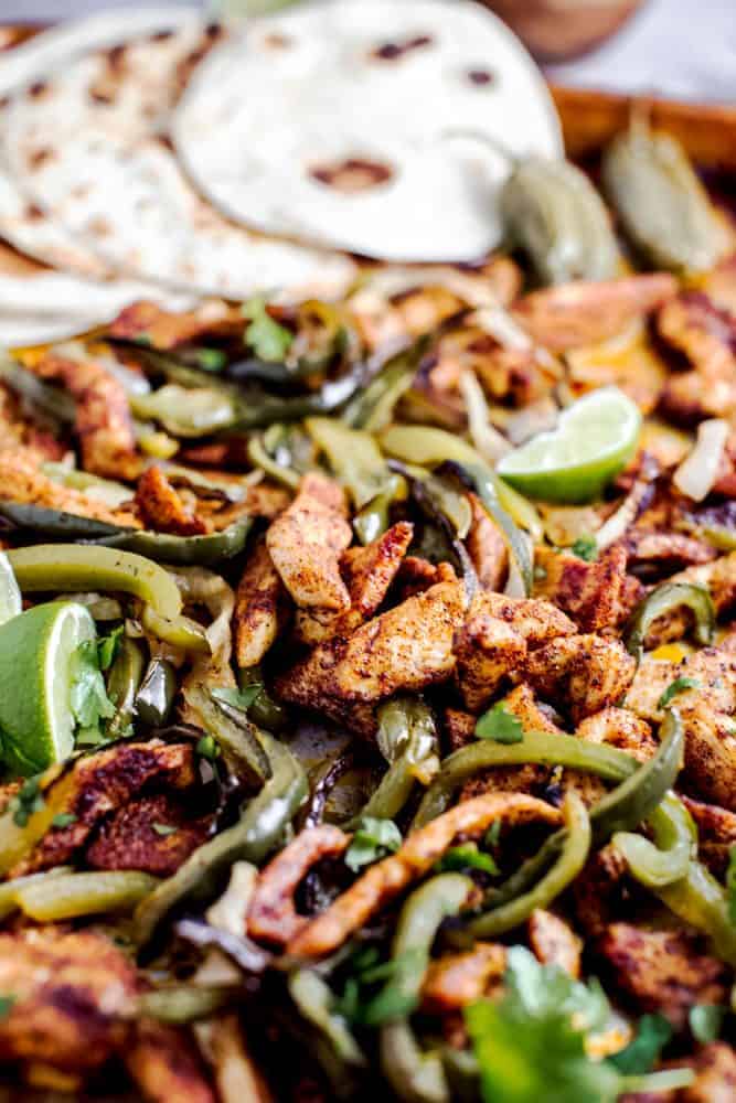 Sheet Pan Salsa Verde Chicken Fajitas are the tangy new way to enjoy a delicious taco Tuesday, or Wednesday, or any other day of the week. This healthy meal is made in minutes, leaving you with little cleanup, and tons of leftover salsa verde. Sheet Pan Salsa Verde Chicken Fajita cooked ingredients up close.