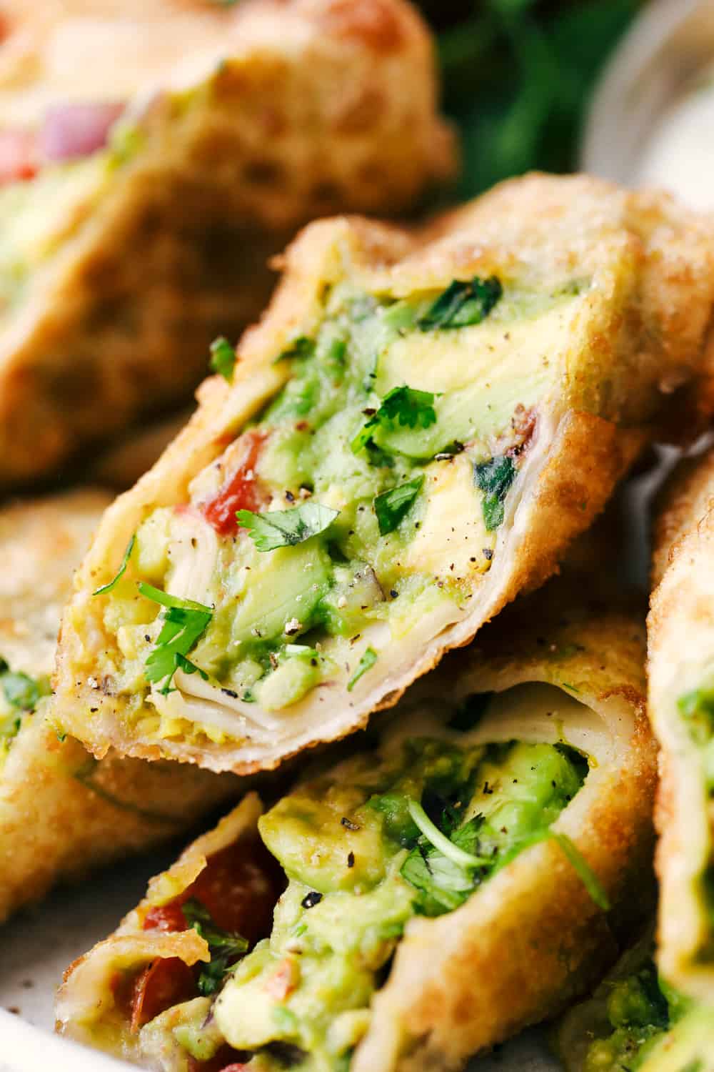 Avocado Egg Rolls are crispy on the outside with an avocado mixtureย inside that is bursting with flavor! Once these hit the table theyย don't last long! Close up of avocado egg roll