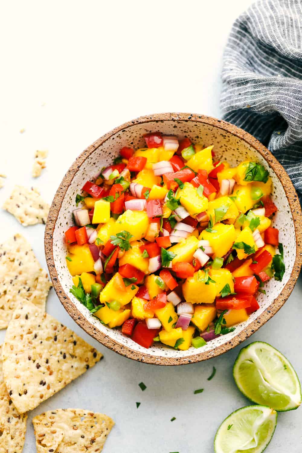 Fresh and Easy Mango Salsa is a colorful dish that is packed with juicy mangos, crunchy red onions and bell peppers, a little spice from a jalapeño and cooled down with a squeeze of fresh lime juice flavor! Enjoy this sweet and savory salsa this mango season. Overhead view of mango salsa in a bowl.