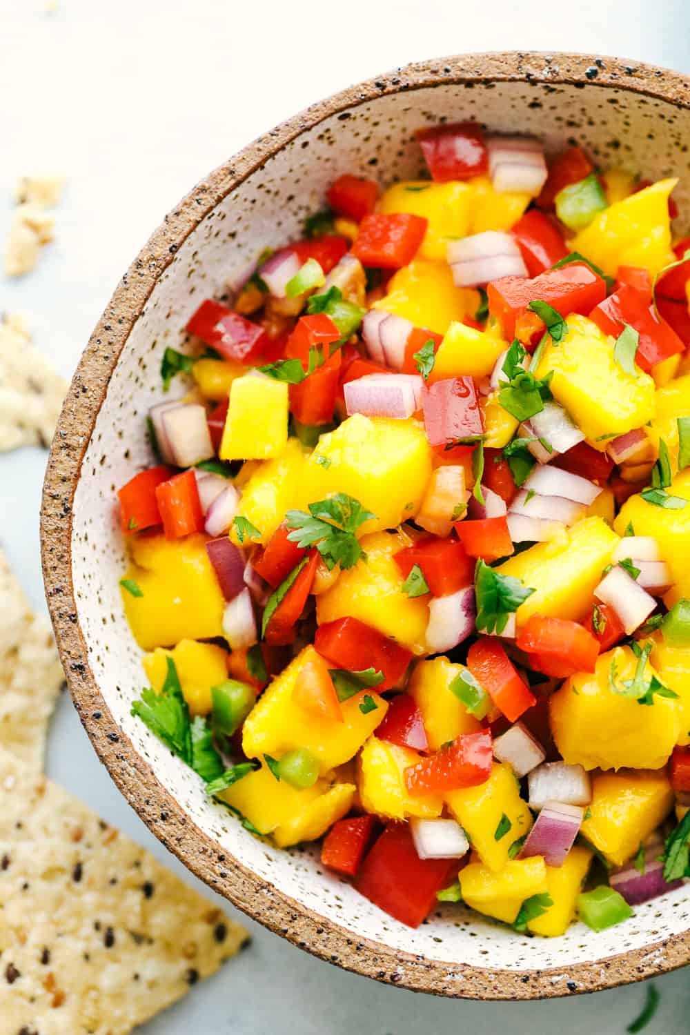 Fresh and Easy Mango Salsa is a colorful dish that is packed with juicy mangos, crunchy red onions and bell peppers, a little spice from a jalapeño and cooled down with a squeeze of fresh lime juice flavor! Enjoy this sweet and savory salsa this mango season. Mango salsa in a bowl.