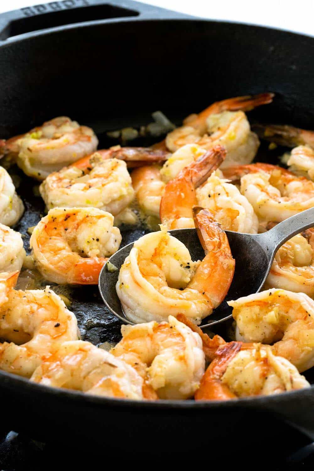 Lemon Garlic Shrimp and Asparagus Skillet is a quick and healthy one pan meal loaded with fresh citrus flavors. Tender jumbo shrimp are marinated in lemon, garlic, olive oil, and seasonings before they hit the pan. The seafood is sauteed with crisp asparagus and tomatoes for a wholesome dinner. shrimp cooking in a cast iron skillet