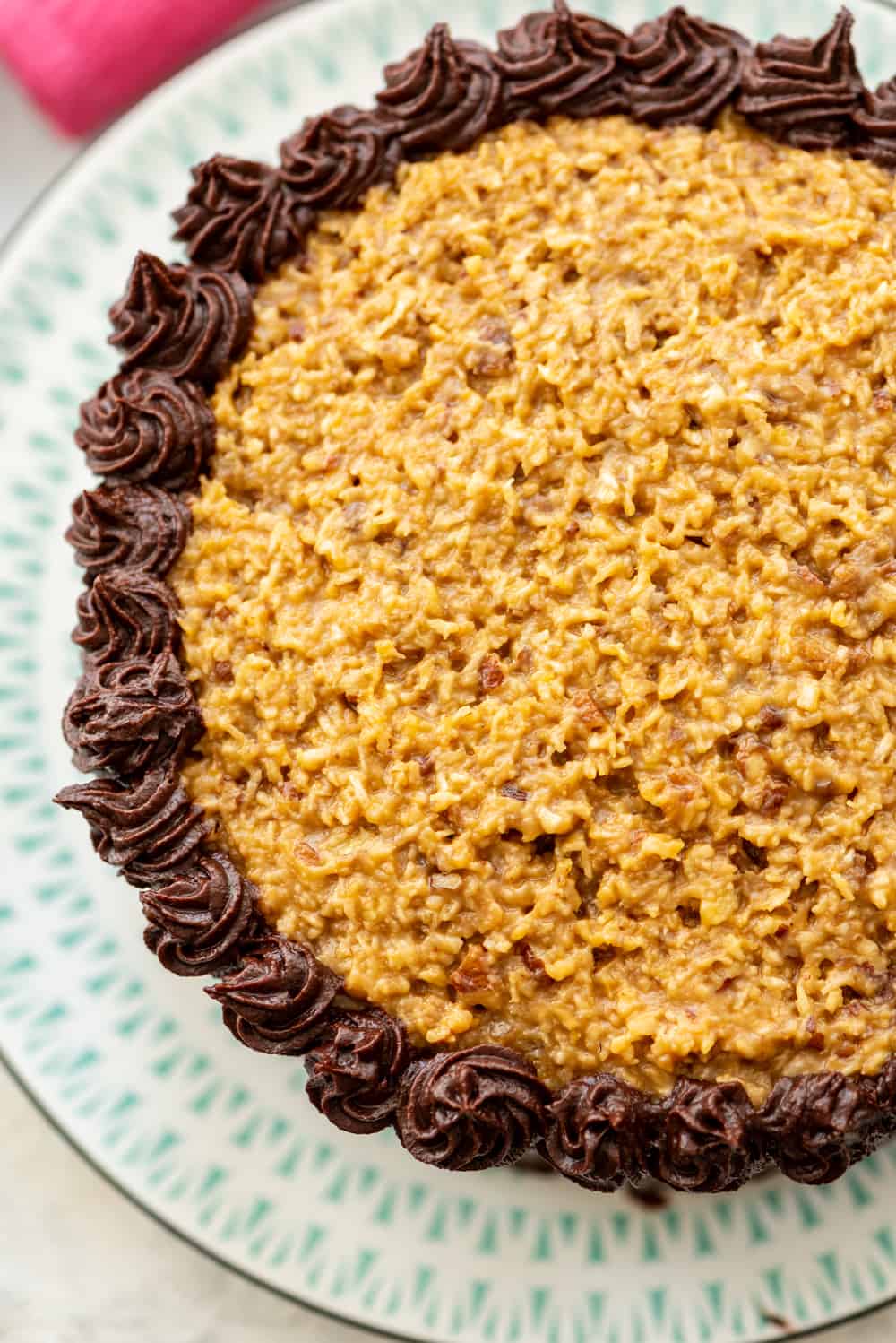 Homemade German Chocolate Cake, with two layers of scratch made cake, a sticky coconut pecan topping, and fudge frosting is everyone's favorite cake! Homemade German Chocolate Cake on a plate.