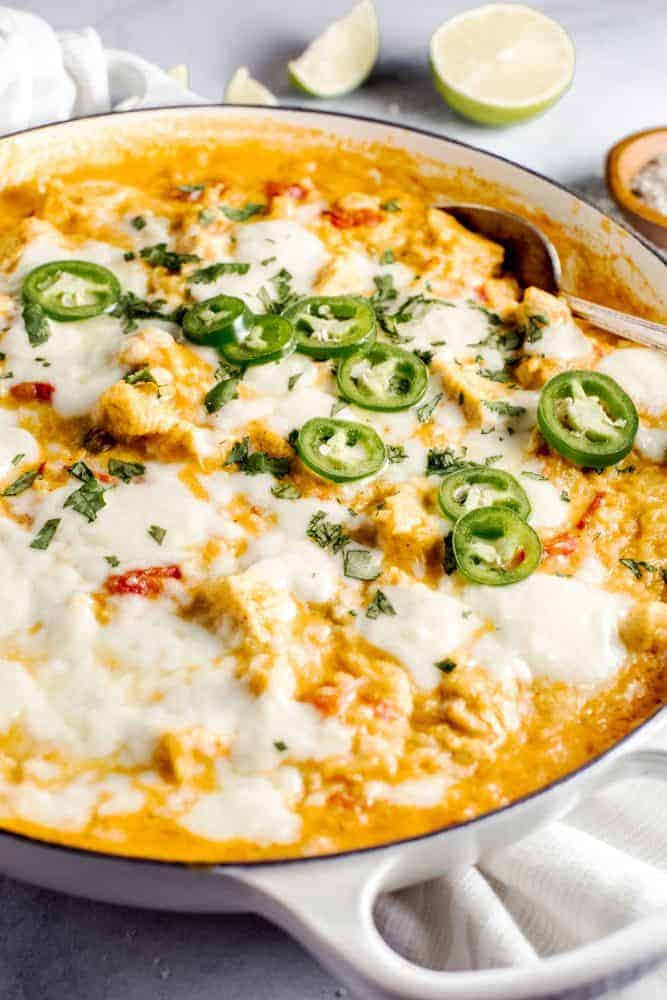 This Queso Chicken Skillet has the potential to become your families new favorite weeknight dinner. Creamy queso melted together with tender chicken, diced chilis and tomatoes, all mixed into tasty yellow rice create the perfect cheesy dinner. Queso chicken skillet in a pan.