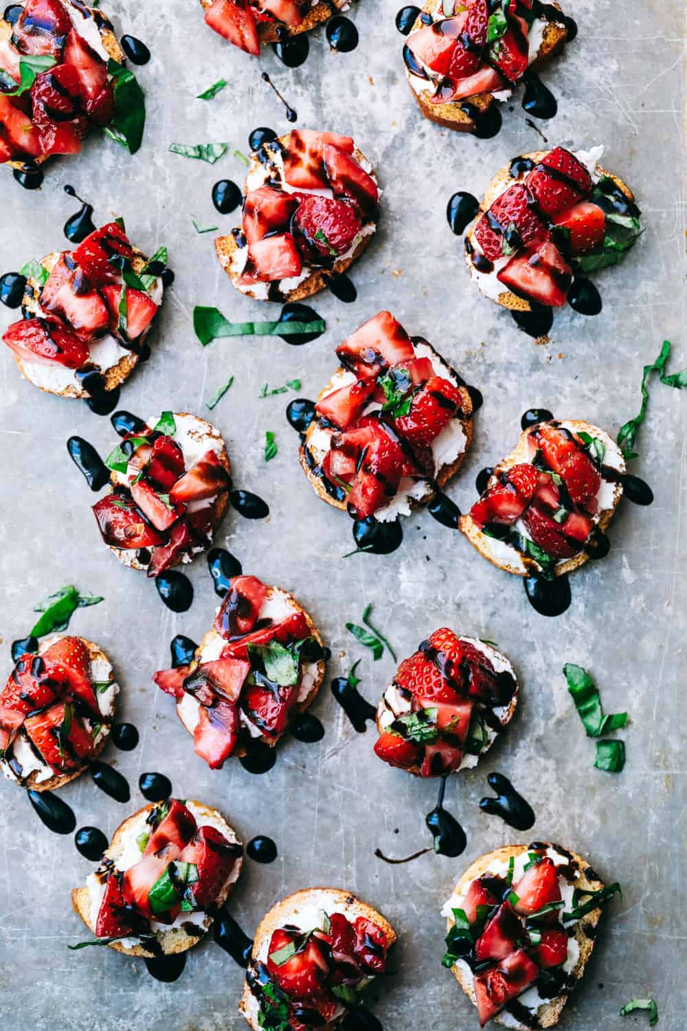 Easy Strawberry Bruschetta is an elegant appetizer that is vibrant and full of flavor! Fresh cut strawberries, warm goat cheese layered on a crunchy baguette slice, topped with a creamy balsamic glaze that melts in your mouth with every bite! Strawberry bruschetta on a pan