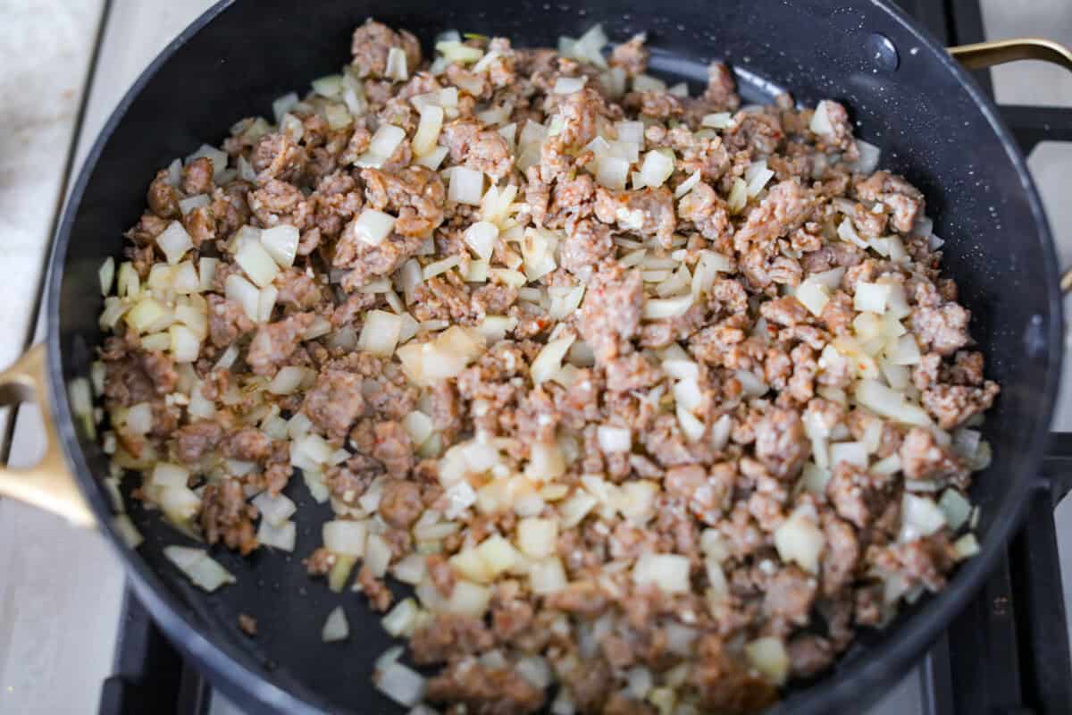 Baked spaghetti is the ultimate comfort food, with noodles that soak up all of the rich sauce as they finish cooking, making every bite extra flavorful. Plus, itโs a lifesaver on busy days. You can prep it ahead, pop it in the oven, and still have a cozy, home-cooked meal without the stress! Onions and garlic cooking with the Italian sausage.