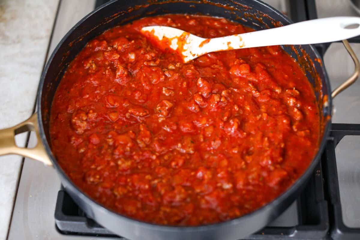 Baked spaghetti is the ultimate comfort food, with noodles that soak up all of the rich sauce as they finish cooking, making every bite extra flavorful. Plus, itโs a lifesaver on busy days. You can prep it ahead, pop it in the oven, and still have a cozy, home-cooked meal without the stress! Overhead shot of marinara added to the meat and onion mixture.