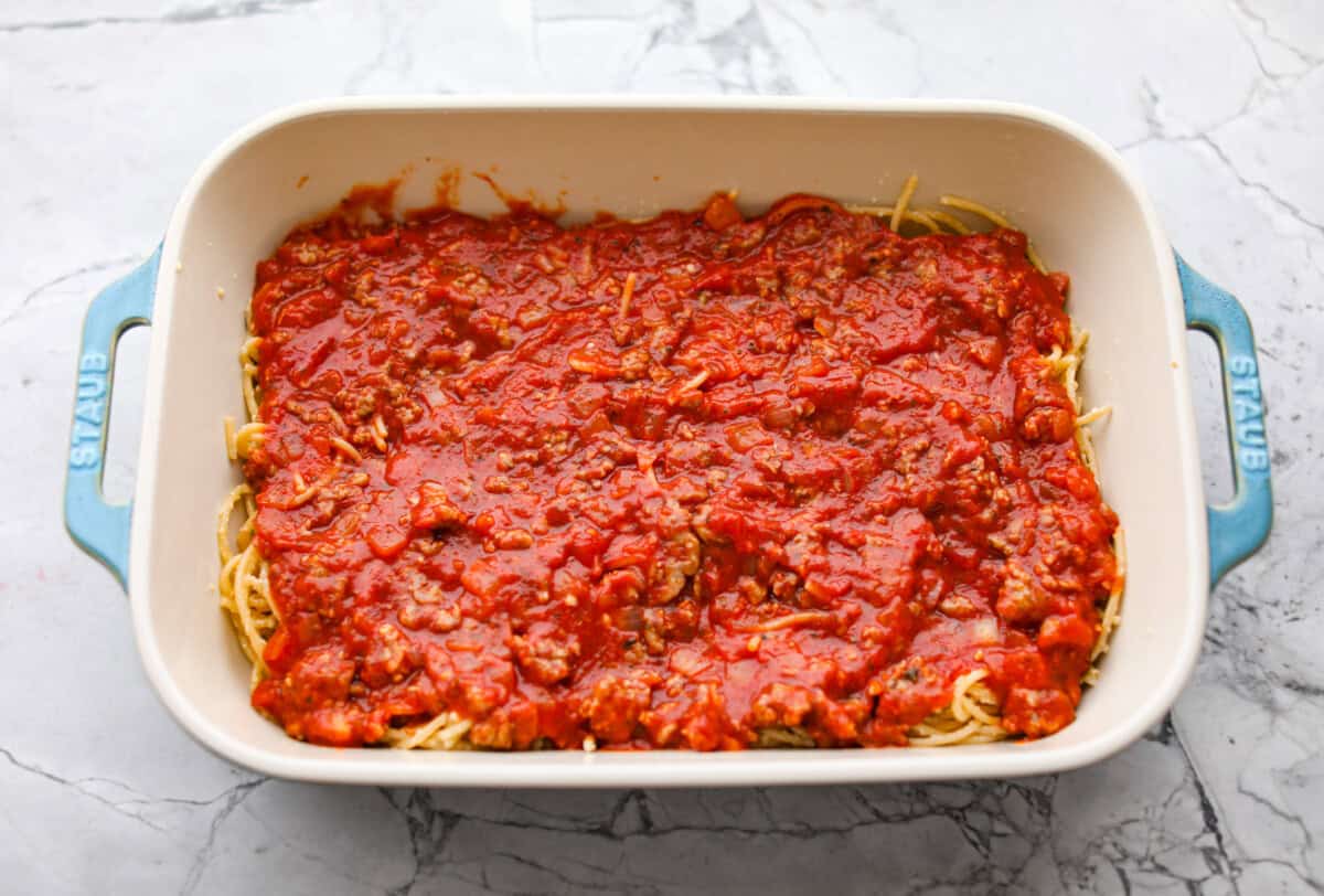 Baked spaghetti is the ultimate comfort food, with noodles that soak up all of the rich sauce as they finish cooking, making every bite extra flavorful. Plus, itโs a lifesaver on busy days. You can prep it ahead, pop it in the oven, and still have a cozy, home-cooked meal without the stress! Meat sauce layered on top of the noodles in the baking dish.